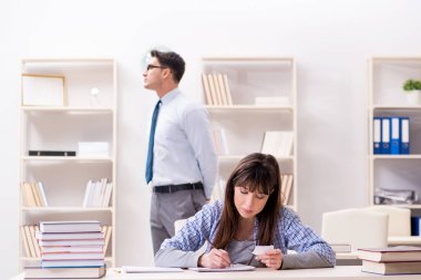 Erkek öğretim görevlisi bayan öğrenciye ders veriyor.