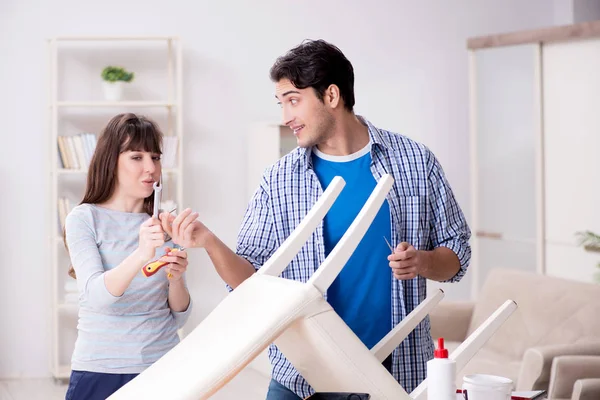 Vrouw helpen man naar reparatie kapotte stoel thuis — Stockfoto