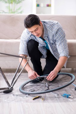 Evde bisiklet tamir eden genç bir adam.