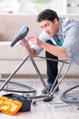 Evde bisiklet tamir eden genç bir adam.