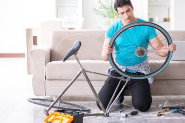 Evde bisiklet tamir eden genç bir adam.