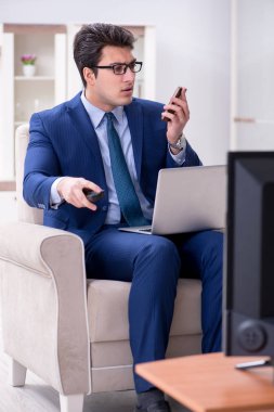 İş adamı ofiste televizyon izliyor.