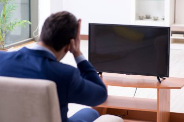 İş adamı ofiste televizyon izliyor.