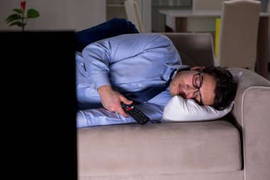 İşadamı gece geç saatte televizyon izliyor.