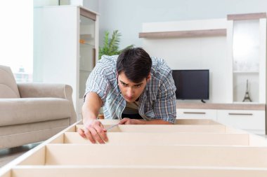 Adam evde mobilya montajı yapıyor.