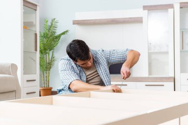 Adam evde mobilya montajı yapıyor.