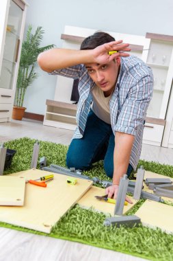 Adam evde mobilya montajı yapıyor.