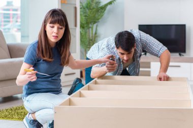 Yeni evde mobilya montajı yapan genç bir aile.