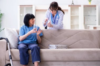 Genç doktor yaşlı kadını muayene etmek için ziyaret ediyor.