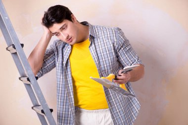 Evdeki duvara alçı yapıştıran genç adam.