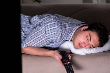 Genç adam gece geç saatte televizyon izliyor.