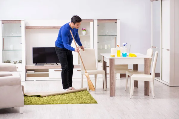 Молодий чоловік прибирає підлогу з мітлою — стокове фото