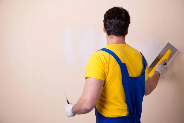 Empregado jovem empreiteiro aplicando gesso na parede — Fotografia de Stock