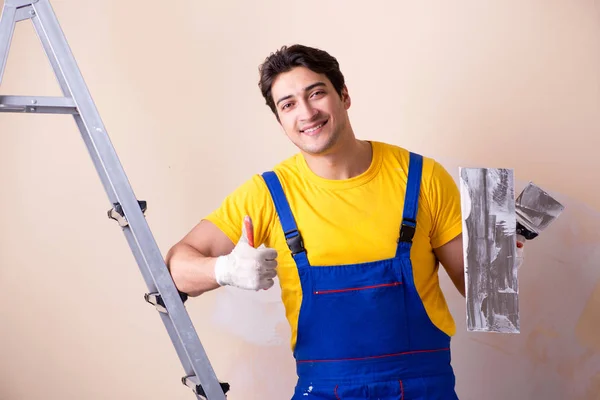 Empregado jovem empreiteiro aplicando gesso na parede — Fotografia de Stock