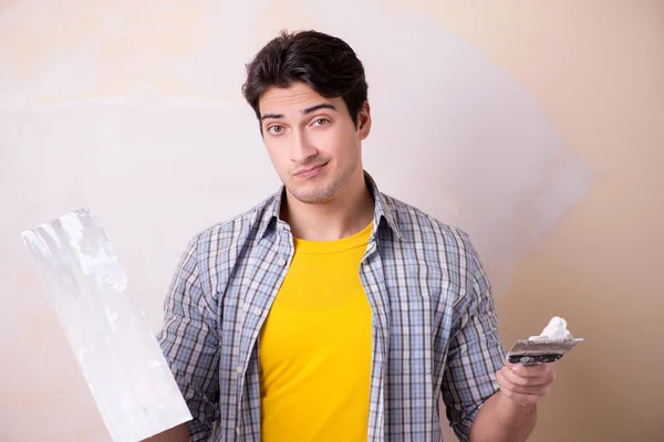 Hombre joven aplicando yeso en la pared en casa — Foto de Stock