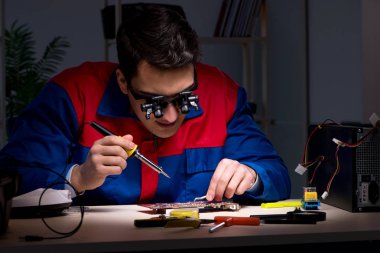 Bilgisayar uzmanı gece geç saatlerde bilgisayarı tamir ediyor.