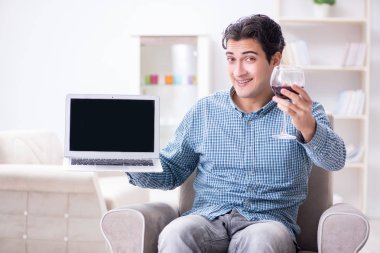 Genç adam evde şarap içiyor.