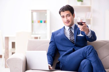 İş adamı evde oturmuş şarap içiyor.