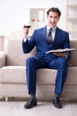 İş adamı evde oturmuş şarap içiyor.