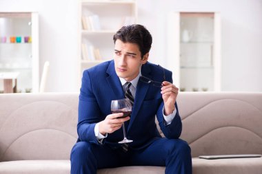 İş adamı evde oturmuş şarap içiyor.