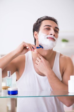 Genç yakışıklı adam sabah erkenden tıraş oluyor.