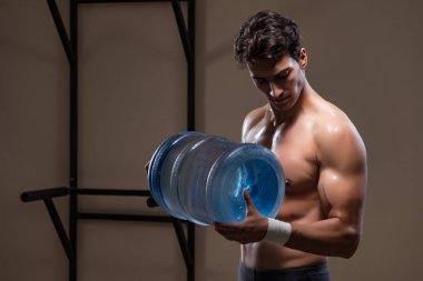 Büyük su şişeli kaslı adam.