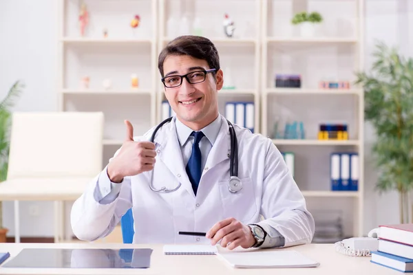 Junger Arzt sitzt im Büro — Stockfoto