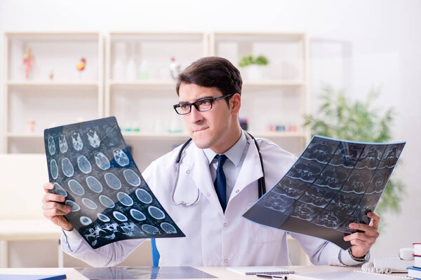 Young doctor looking at x-ray images in clinic