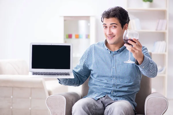 Genç adam evde şarap içiyor.