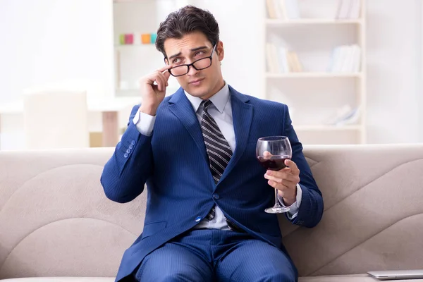 Бизнесмен пьет вино сидя дома — стоковое фото