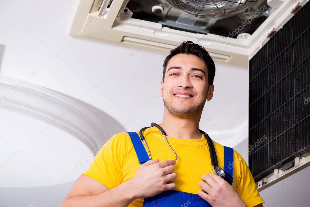 Repairman repairing ceiling air conditioning unit