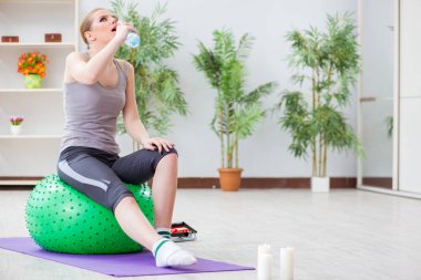 Spor salonunda denge topuyla egzersiz yapan genç bir kadın.