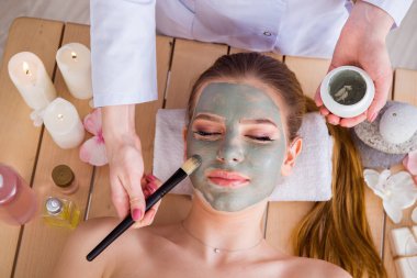 Yüz maskeli, spa sağlık konsepti olan genç bir kadın.