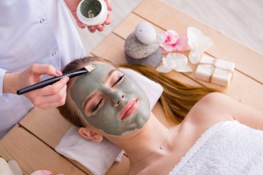 Yüz maskeli, spa sağlık konsepti olan genç bir kadın.
