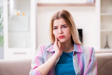 Evde acı çeken genç bir kadın.