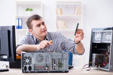 Genç teknisyen atölyede bilgisayar tamir ediyor.