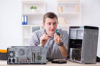 Genç teknisyen atölyede bilgisayar tamir ediyor.