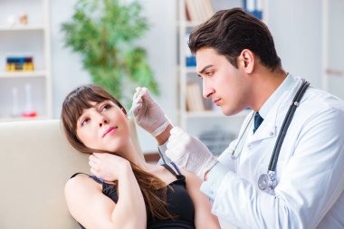 Doctor checking patients ear during medical examination clipart