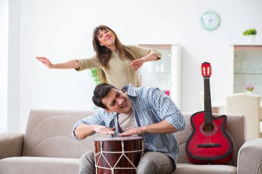Genç bir aile evde şarkı söylüyor ve müzik çalıyor.
