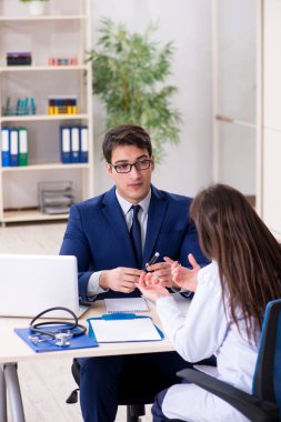 İş adamı doktorla sağlık sorunlarını tartışıyor