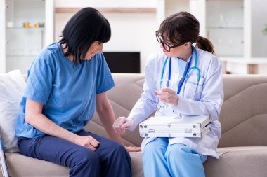 Genç doktor yaşlı kadını muayene etmek için ziyaret ediyor.