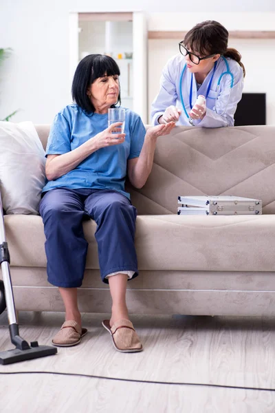Jonge arts bezoekt oude volwassen vrouw voor check-up — Stockfoto