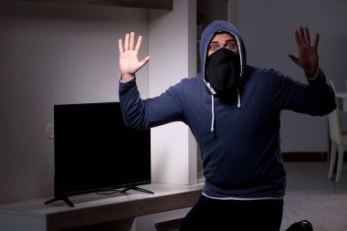 Hırsız, apartmandan televizyon çalıyor.