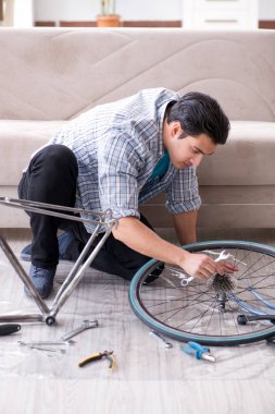 Evde bisiklet tamir eden genç bir adam.