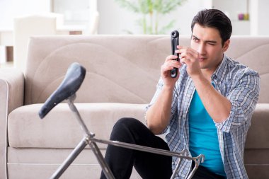 Evde bisiklet tamir eden genç bir adam.