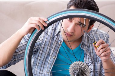 Evde bisiklet tamir eden genç bir adam.