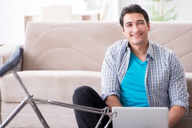 Evde bisiklet tamir eden genç bir adam.