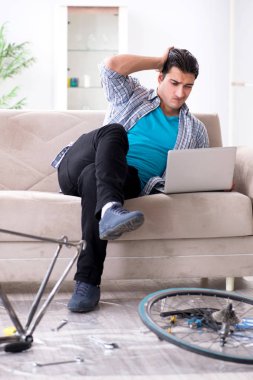 Evde bisiklet tamir eden genç bir adam.