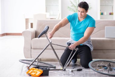 Evde bisiklet tamir eden genç bir adam.