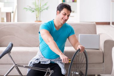 Evde bisiklet tamir eden genç bir adam.